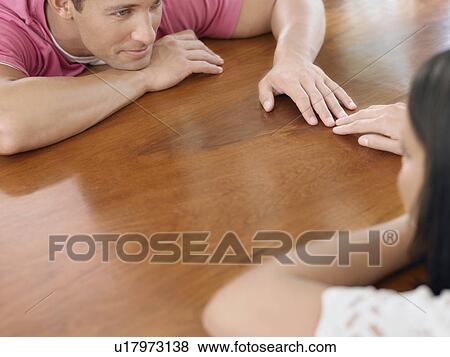 Stock Photo - Affectionate Young Couple Touching Hands. Fotosearch