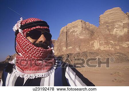 Stock Photo - Arab Man in turban Wearing Sunglasses standing in desert landscape. Fotosearch