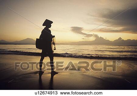 Stock Image - Asian fisherman on shore watching sunset. Fotosearch