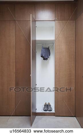 Stock Image - Athletic shoes and running shorts in locker with open door. Fotosearch