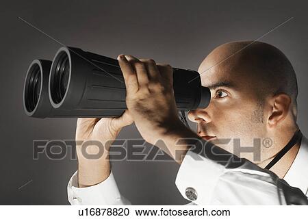 Stock Image - Balding Middle-aged businessman looking through large binoculars. Fotosearch