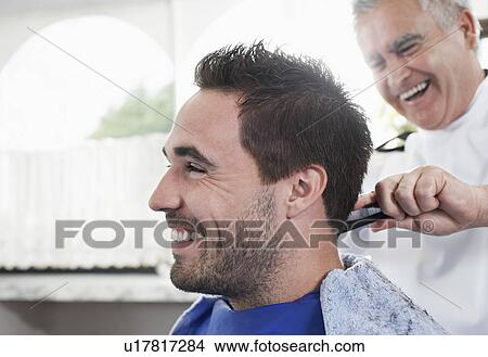Picture - Barber cutting mans hair in barber shop close-up. Fotosearch