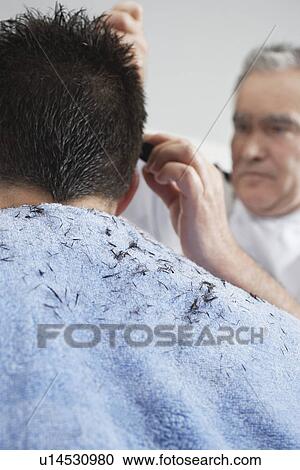 Stock Image - Barber cutting mans hair in barber shop close-up. Fotosearch