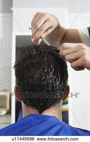 Stock Photo - Barber cutting mans hair in barber shop close-up. Fotosearch