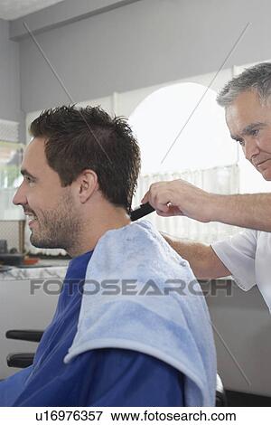 Barber cutting mans hair in barber shop View Large Photo Image Stock Photo - Barber cutting mans hair in barber shop. Fotosearch