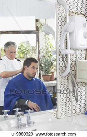 Stock Photo - Barber cutting mans hair in barber shop. Fotosearch