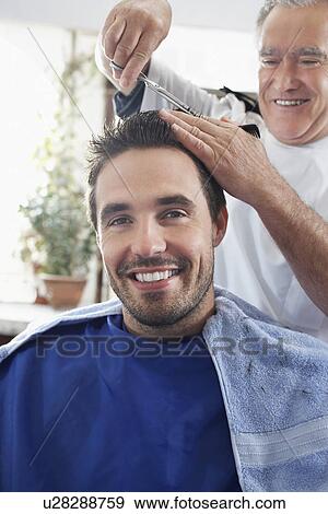 Stock Photo - Barber cutting mans hair in barber shop. Fotosearch