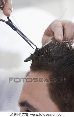 Stock Photography - Barber cutting mans hair in barber shop. Fotosearch