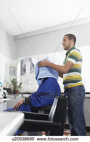 Stock Photo - Barber preparing man for haircut in barber shop. Fotosearch