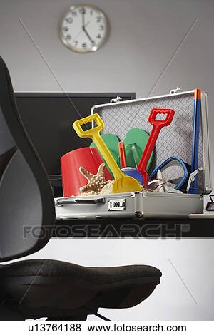 Stock Photo - Beach toys in open business case in office. Fotosearch