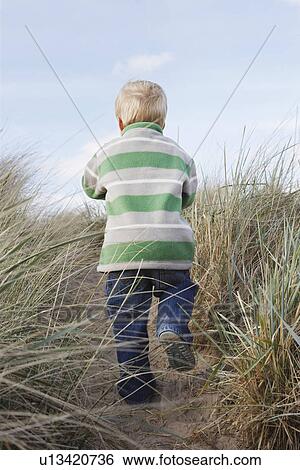 Boy (3-4) walking on path among long grass View Large Photo Image Stock Photograph - Boy (3-4) walking on path among long grass. Fotosearch