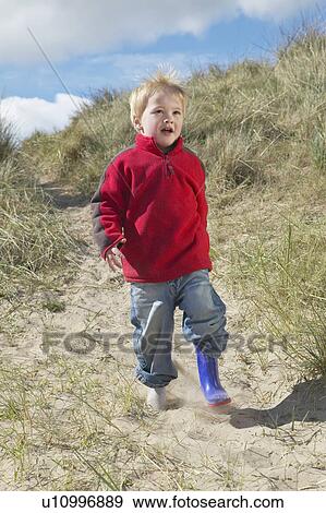 Stock Photo - Boy (3-4) walking on sand dunes. Fotosearch