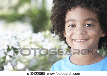 Stock Image - Boy (5-6 years) smiling outdoors portrait close-up. Fotosearch