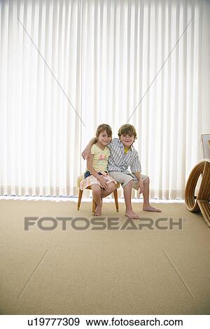Boy (7-9) and girl (5-6) sitting on stool in room View Large Photo Image Stock Photo - Boy (7-9) and girl (5-6) sitting on stool in room. Fotosearch