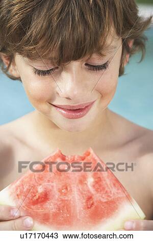 Stock Image - Boy (7-9) eating watermelon close-up. Fotosearch