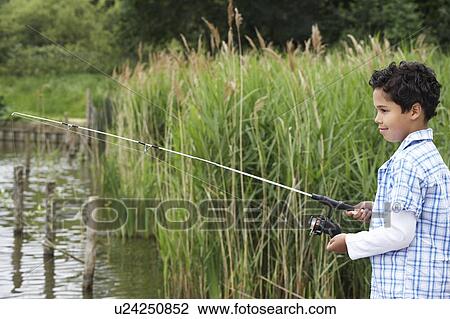 Stock Image - Boy (7-9) fishing in river. Fotosearch