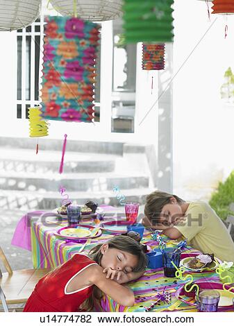 Stock Image - Boy and girl (7-9) sleeping at table after birthday party. Fotosearch