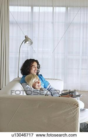Boyfriend and girlfriend sitting on sofa watching television View Large Photo Image Stock Photo - Boyfriend and girlfriend sitting on sofa watching television. Fotosearch