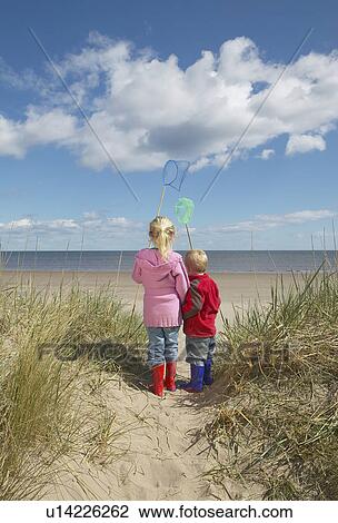 Brother and sister (4-6) with fishing nets standing on sand dunes View Large Photo Image Stock Image - Brother and sister (4-6) with fishing nets standing on sand dunes. Fotosearch