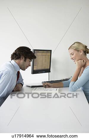 Picture - Business couple sitting at desk side view. Fotosearch