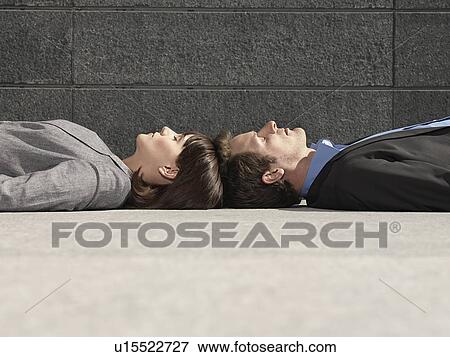 Business man and woman lying on ground head to head side view View Large Photo Image Stock Photo - Business man and woman lying on ground head to head side view. Fotosearch