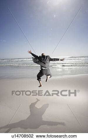 Business man jumping mid air on beach back view View Large Photo Image Stock Image - Business man jumping mid air on beach back view. Fotosearch