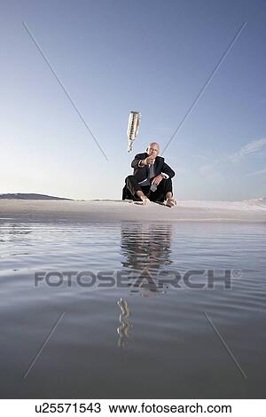 Business man sitting on beach throwing message in bottle into sea low angle view View Large Photo Image Stock Image - Business man sitting on beach throwing message in bottle into sea low angle view. Fotosearch