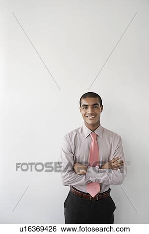 Stock Photograph - Business man standing against wall in office portrait. Fotosearch
