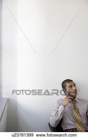 Stock Photo - Business man using mobile phone in office elevated view. Fotosearch