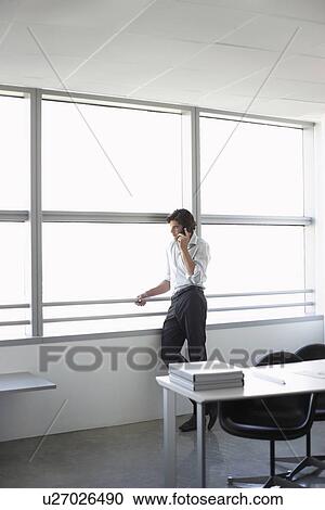Business man using mobile phone looking out of office window View Large Photo Image Stock Image - Business man using mobile phone looking out of office window. Fotosearch