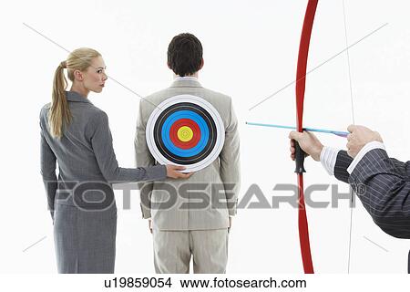 Business woman holding target to man's back while other man (close-up of hands) aims bow and arrow against white background View Large Photo Image Picture - Business woman holding target to man's back while other man (close-up of hands) aims bow and arrow against white background. Fotosearch