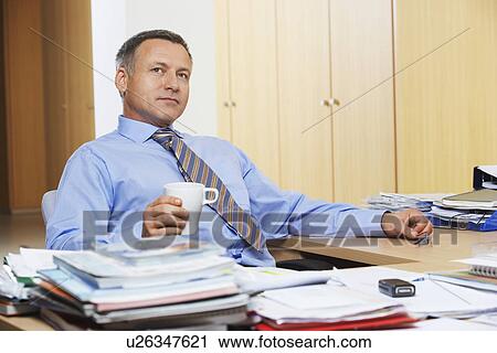 Stock Image - Businessman at desk looking away. Fotosearch