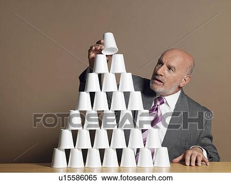 Businessman Building Pyramid of Cups on table View Large Photo Image Stock Photography - Businessman Building Pyramid of Cups on table. Fotosearch