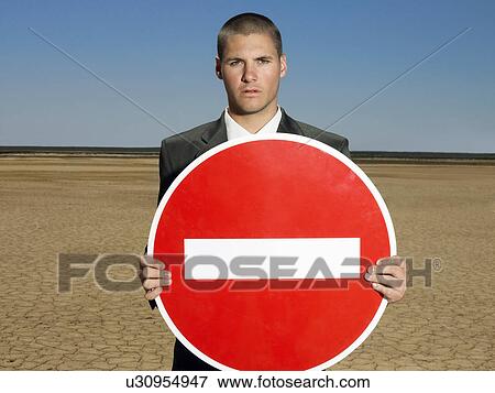 Businessman holding 'no entry' sign in desert half length View Large Photo Image Stock Photo - Businessman holding 'no entry' sign in desert half length. Fotosearch