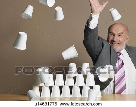 Businessman knocking down pyramid of plastic cups View Large Photo Image Stock Photography - Businessman knocking down pyramid of plastic cups. Fotosearch