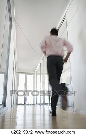 Stock Image - Businessman Running in Corridor low angle back view.. Fotosearch