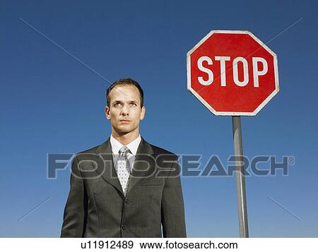 Businessman standing next to stop sign half length View Large Photo Image Stock Photo - Businessman standing next to stop sign half length. Fotosearch
