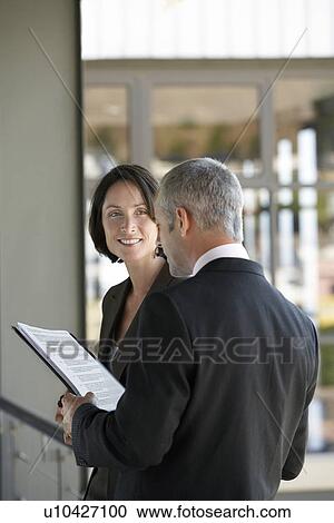 Stock Image - Businessman talking to businesswoman.. Fotosearch