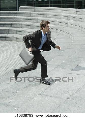 Stock Image - Businessman with briefcase running up steps outdoors side view. Fotosearch