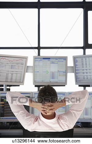 Businessman with Hands Behind Head watching computer screens back view. View Large Photo Image Picture - Businessman with Hands Behind Head watching computer screens back view.. Fotosearch