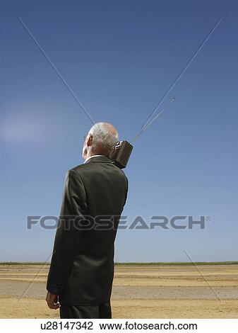 Businessman with radio on shoulder in desert back view View Large Photo Image Stock Image - Businessman with radio on shoulder in desert back view. Fotosearch