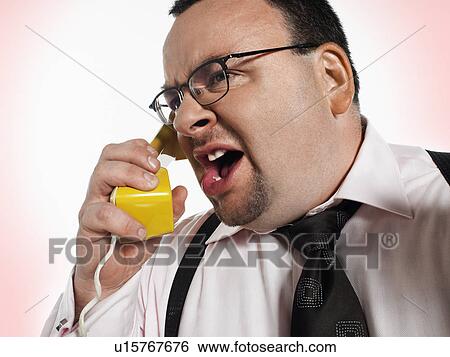 Stock Photograph - Businessman yelling into phone close-up. Fotosearch