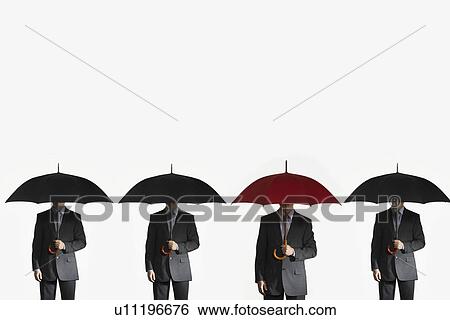 Stock Photograph - Businessmen holding umbrellas standing side by side one red umbrella. Fotosearch