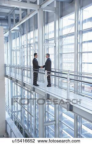 Businessmen shaking hands in modern building View Large Photo Image Stock Image - Businessmen shaking hands in modern building. Fotosearch