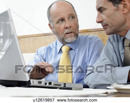 Businessmen using laptop indoors View Large Photo Image Stock Photo - Businessmen using laptop indoors. Fotosearch
