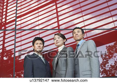 Businesspeople Standing outside beside red Building low angle view View Large Photo Image Stock Photo - Businesspeople Standing outside beside red Building low angle view. Fotosearch