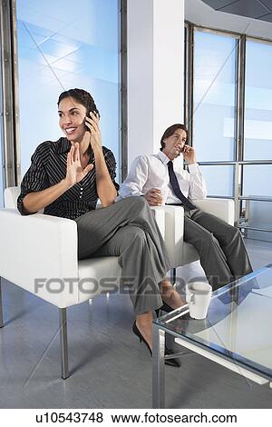 Businesspeople talking on cell phones in office lobby View Large Photo Image Stock Photo - Businesspeople talking on cell phones in office lobby. Fotosearch
