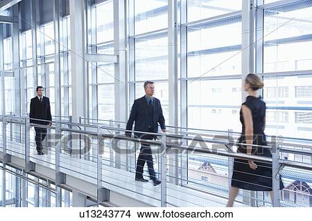 Businesspeople walking in modern building View Large Photo Image Picture - Businesspeople walking in modern building. Fotosearch