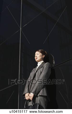 Stock Photo - Businesswoman Leaning eyes closed Against Wall outside. Fotosearch