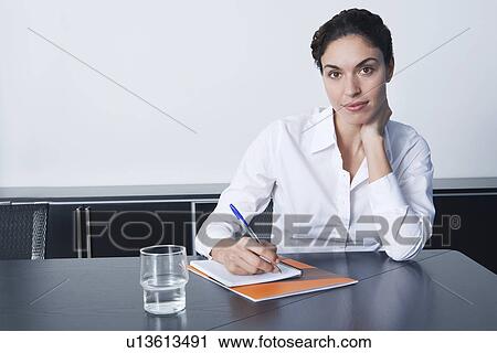 Stock Image - Businesswoman sitting at desk in office portrait. Fotosearch